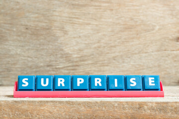 Tile letter on red rack in word surprise on wood background