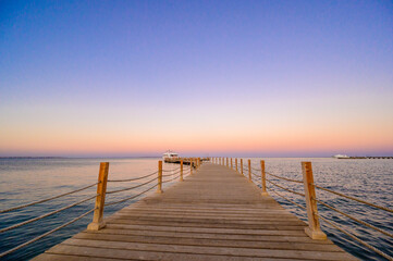 Fototapeta na wymiar Wooden Pier on Red Sea in Hurghada at sunset and luxury yacht, View of the promenade boardwalk - Egypt, Africa