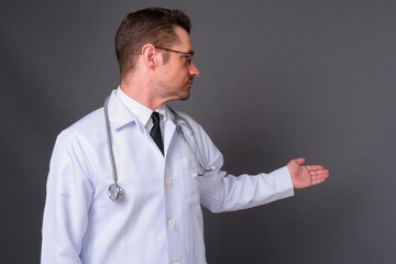 Portrait of handsome bearded man doctor against gray background