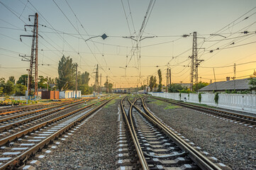 Fototapeta na wymiar Railroad switch lines diverging in different directions at the station in the evening at sunset.