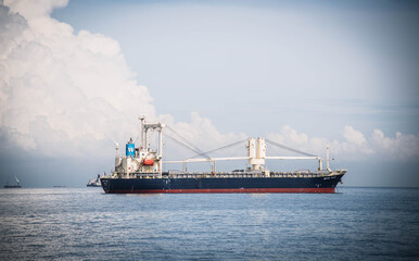 A cargo ship is parked in the middle of the sea waiting to be loaded into a deep-sea port in Si...