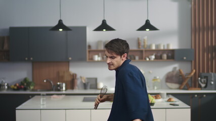 Cheerful man singing song in whisker at home. Happy guy feeling as rockstar