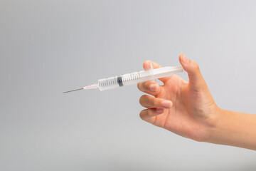 Hand holding syringe on gray background
