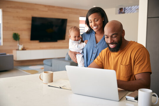 African American Family With Baby Daughter Using Laptop To Check Finances At Home
