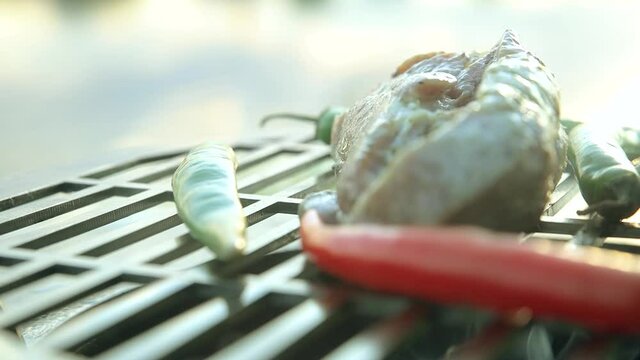 Pieces of steaming grilled pork near chili peppers