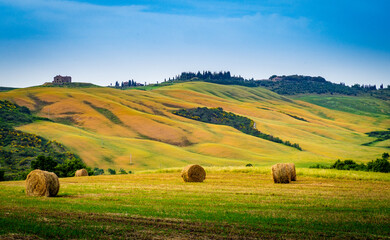 Farmland with hay rolls and farmhouses in Tuscany Italy