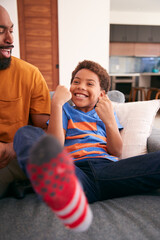 Fototapeta premium Loving African American Father And Son Sitting On Sofa At Home Together