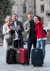 Portrait of positive russian tourists with map and baggage seeing the sights in European city