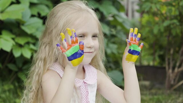 Painted hands of a child with bright colors! Painting and a child. Girl blonde artist