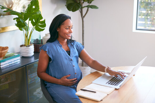 Pregnant African American Woman Using Laptop At Table Working From Home