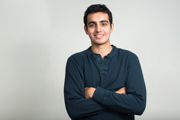 Fototapeta premium Portrait of happy young handsome Indian man smiling with arms crossed