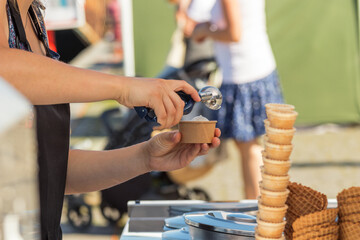 Female vendor sells ice cream at Naplavka farmers street food market in Prague, Czech Republic.
