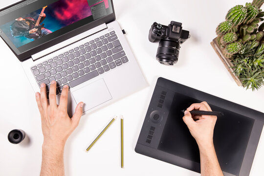 Photographer and graphic designer works on laptop. Flat lay top view of man working on photos in computer. Desk with laptop, camera and hands.
