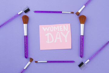 Square frame made of cosmetic brushes. Women's day on a pink paper. Isolated on a purple background.