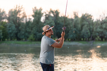 Photo of young man fishing and throwing fishing tackle into river