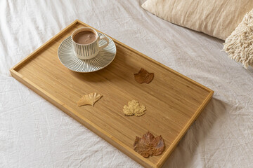 Cozy Cup of Hot Chocolate on wooden tray in bed. Interior home background.