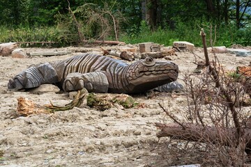 A wooden crocodile crawls on the sand.
