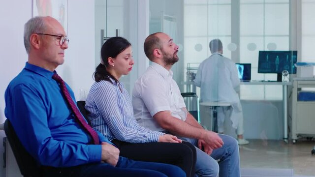 Married couple crying in hospital waiting area after bad news from doctor on virus test results. Senior man waiting for medic to invite him in examination room.