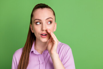 Portrait of interested girl hold hand mouth lips look copyspace share whisper private message wear violet shirt isolated over green color background