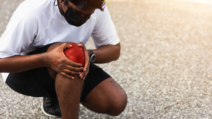 Close up Asian young sport runner black man wear watch sitting hands joint hold knee pain during...
