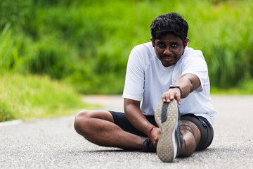 Naklejka na ściany i meble Close up Asian young athlete sport runner black man wear watch he sitting pull toe feet stretching legs and knee before running at outdoor street health park, healthy exercise before workout concept