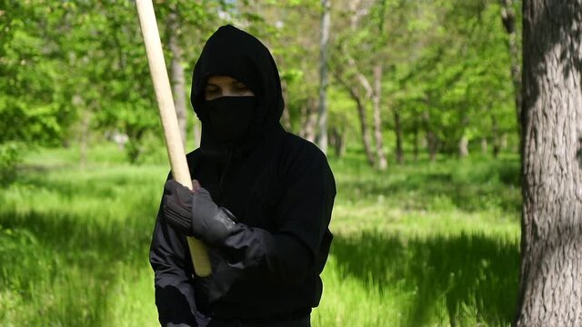 A male ninja in traditional black clothing is training outdoors. Japanese ninja, slow motion