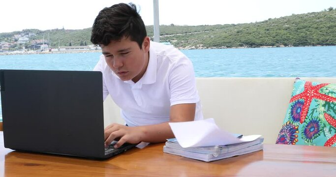 Teenage boy studying on yacht deck Online learning education distance learning for kids at home Homeschooling during quarantine or isolation