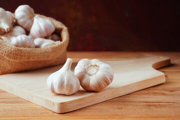 Garlic bulb  on the  wooden 
cutting board  with garlic bulb in  the burlap bags on wooden table.