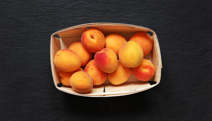 Photography of apricots in a crate on slate background for food illustrations