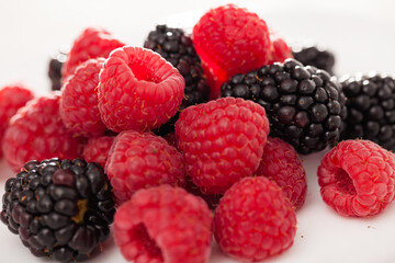 handful of raspberry and blackberry berries on white background