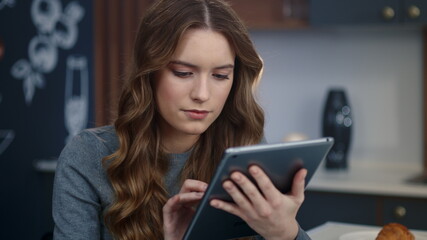 Focused business woman searching information on tablet computer at home office.