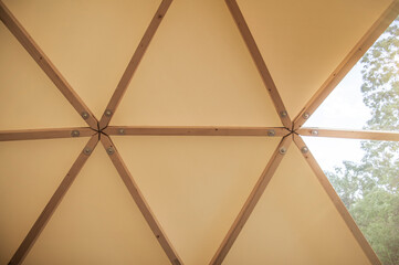 Interior of large geodesic wooden dome tent construction detail with window and view to forest....