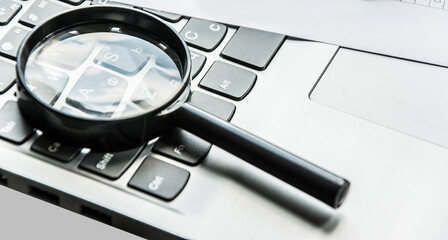 Closeup images of magnifying glass on laptop keyboard, searching, online shopping, and business concept