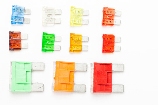 Colorful set of electronic gauges in yellow green orange red and blue on white isolated background in photo studio, car electrical circuit protection devices for sale or replacement in auto service.