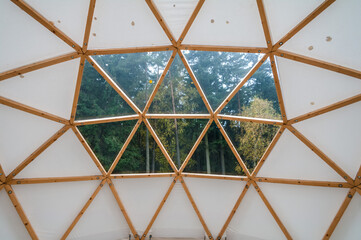 Interior of large geodesic wooden dome tent with window and view to forest. Empty interior glamping tent.