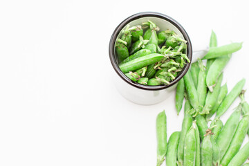 Green peas in a white metal mug and on a plate. Selective focus. Free space for text