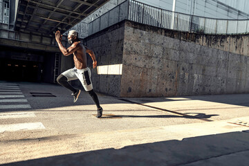 Fototapeta na wymiar Athletic black man is training in urban area while wearing a mask.