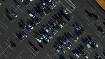 Aerial view of people going at parking lot. Copter flying above cars on parking