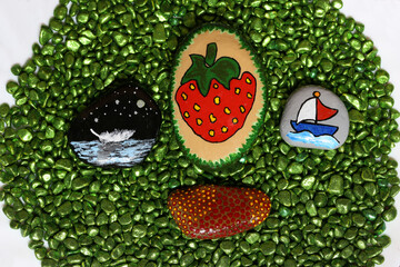 Beautifully painted stones lie on green stones