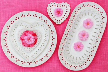 Porcelain heart openwork lace plates, pink Camellia flower, on pink linen tablecloth. Valentine Day or Mother Day, Wedding floral background, copy space