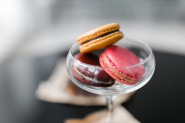 macaroni cookies of different colors in a glass on a black table