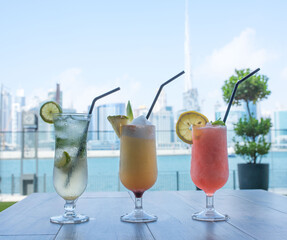 Three Cocktails on a table with Dubai Skyline view in the background