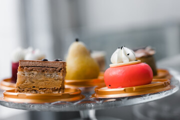 several cakes of different colors on a glass stand