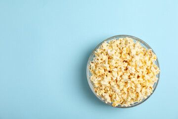 Bowl with popcorn on blue background. Food for watching cinema