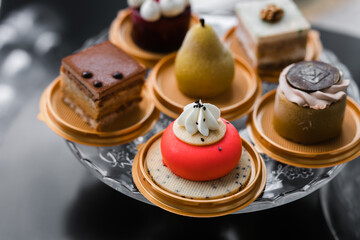 several cakes of different colors on a glass stand