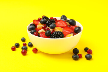 Bowl of fresh fruit salad on yellow background, close up