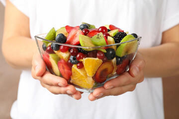 Woman holds bowl of fresh fruit salad, front view