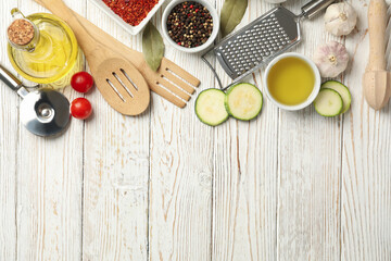 Composition with kitchen cutlery and ingredients for cooking on white wooden background, top view