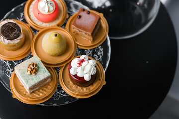 several cakes of different colors on a glass stand
