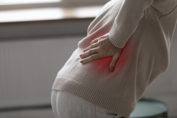 Close up body part of 70s elderly woman got up put hand on lower back relieving ache feel pain in...